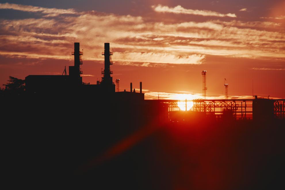 The sun sets behind a power station